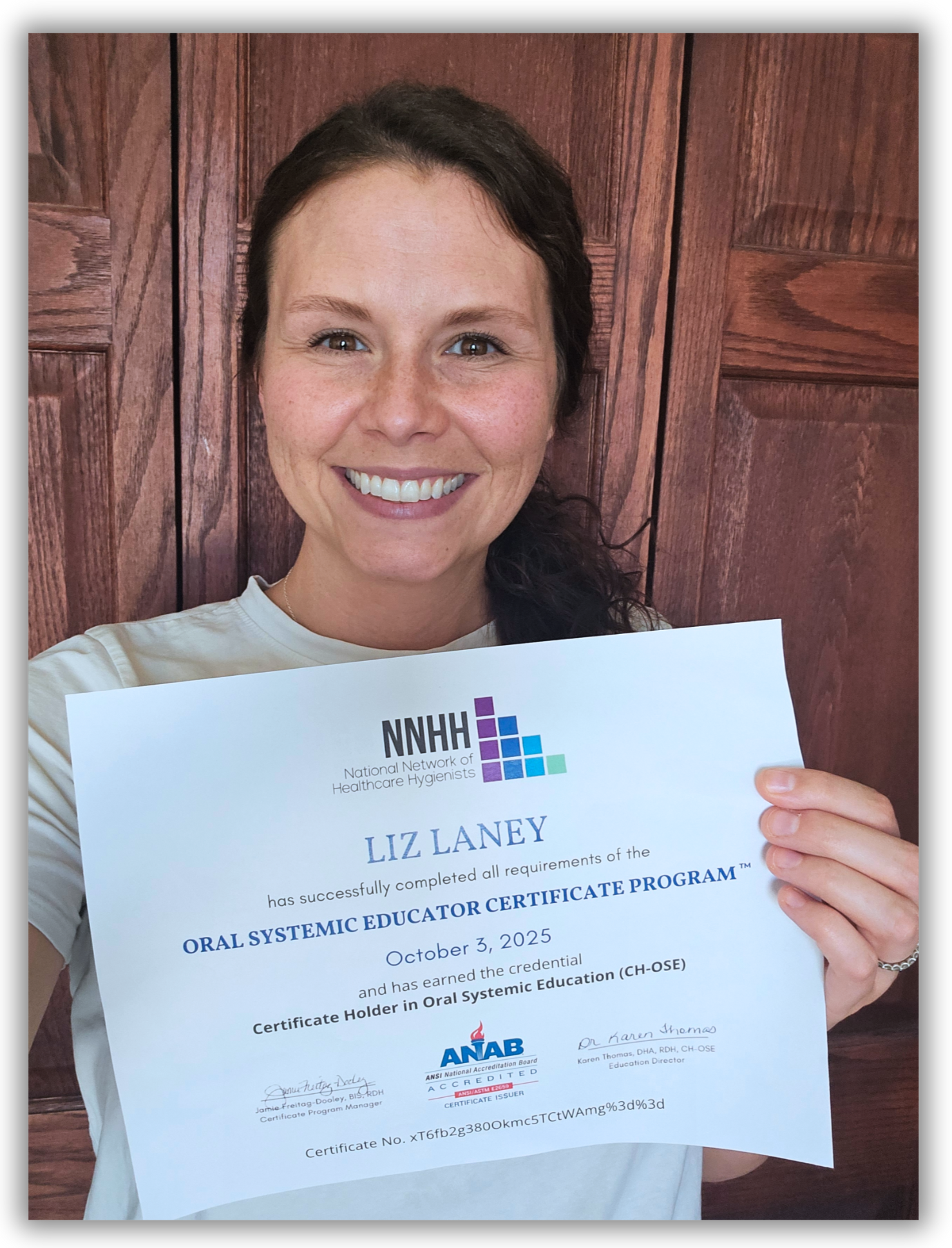 Instructor holding National Network of Healthcare Hygienists Oral Systemic Educator Certificate in front of wood paneling wall 